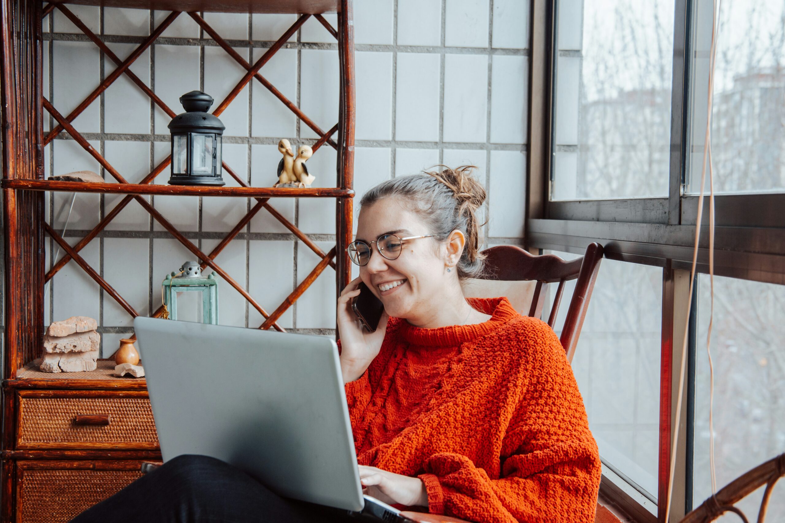Woman speaking on a phone with laptop on her lap